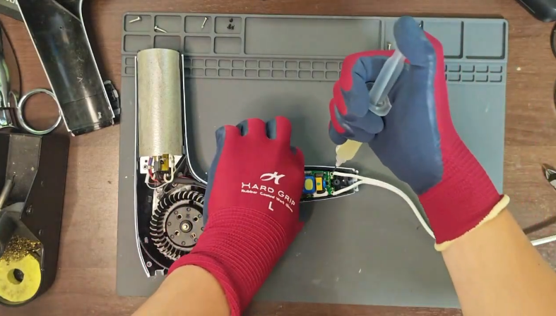 リファドライヤーの内部基板を接点洗浄剤でクリーニングしている修理工程