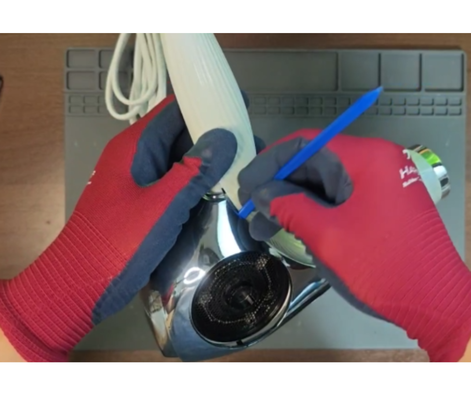 リファドライヤーを分解するために前面カバーをオープンツールでこじ開けている作業工程